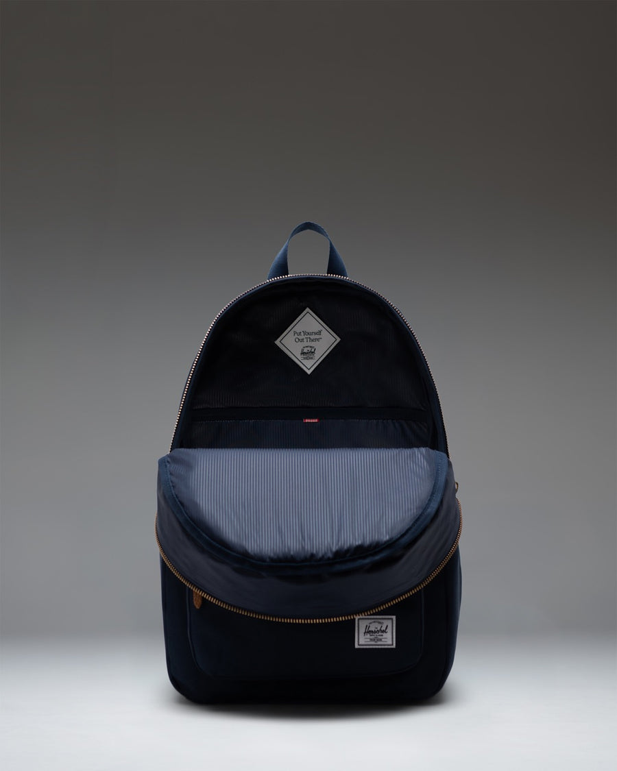 Herschel Supply Co. Settlement Backpack in classic Navy blue, featuring a clean zippered design with a front pocket and iconic woven label.