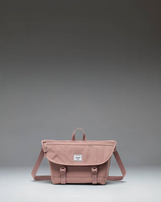Herschel Supply Co Cove Small Messenger bag in Ash Rose pink, viewed from the front, showcasing its compact, structured design.