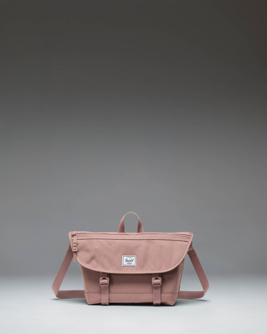 Herschel Supply Co Cove Small Messenger bag in Ash Rose pink, viewed from the front, showcasing its compact, structured design.