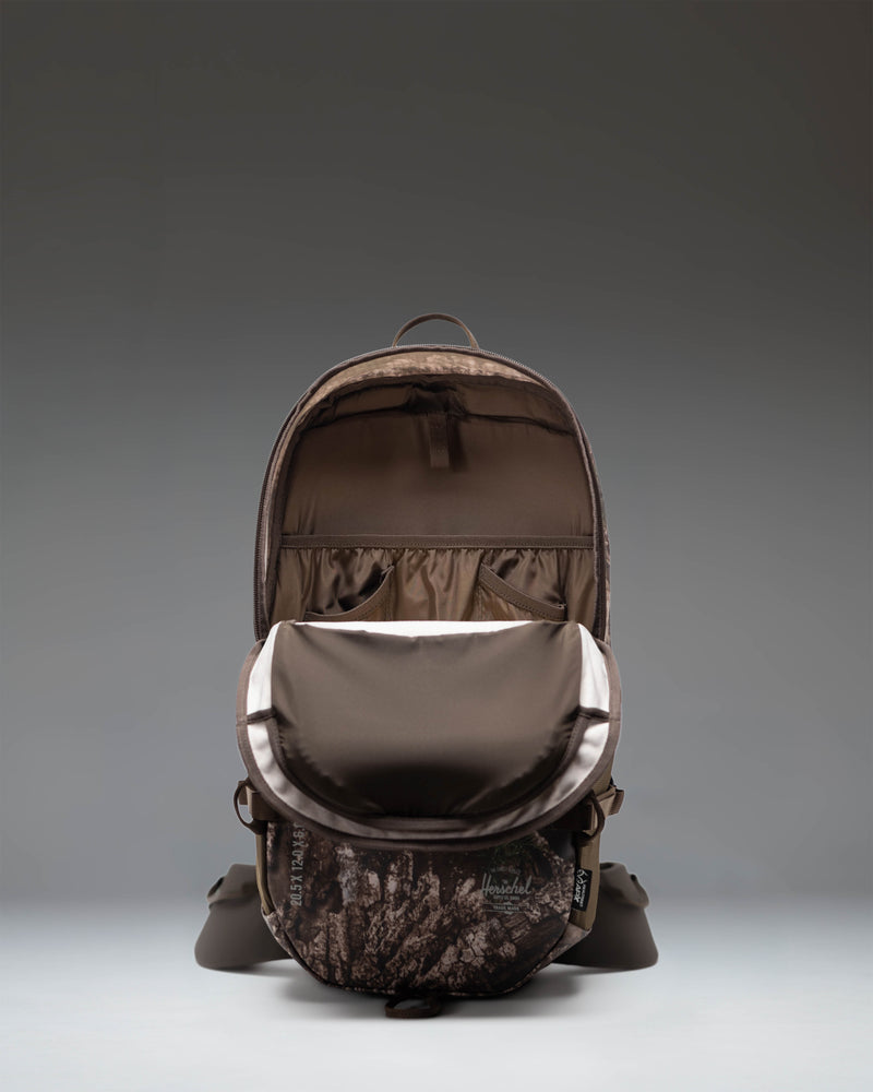 Herschel Supply Co. Realtree All Season Backpack 29 L in Realtree APX Camo pattern showing side pockets and straps.
