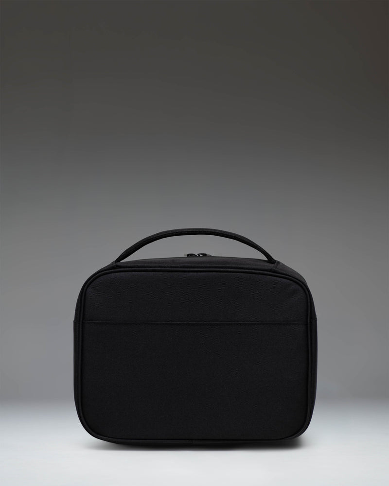 Herschel Supply Co. Pop Quiz Lunch Box in Black Tonal, showing the front view with zippered pocket and top handle.