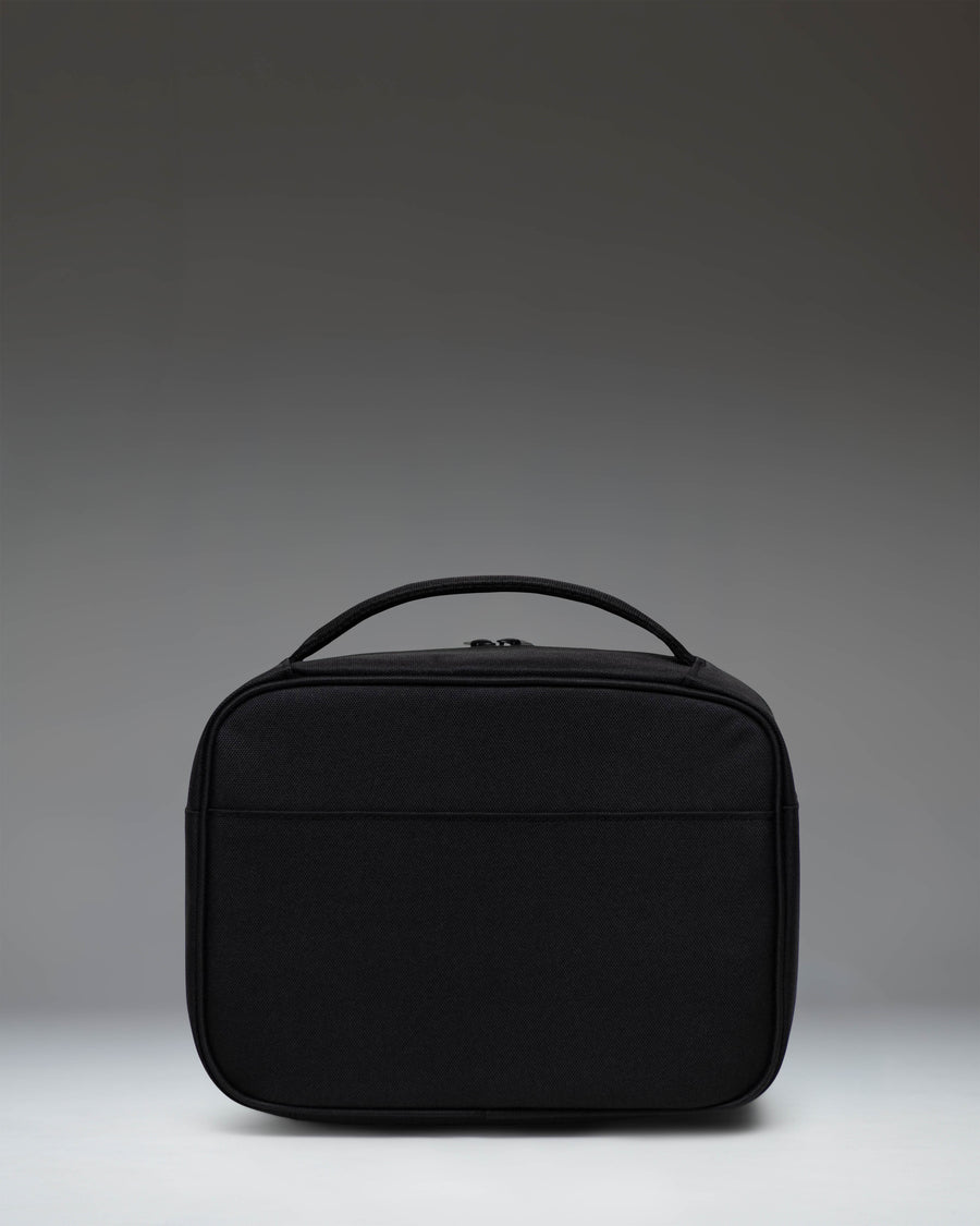 Herschel Supply Co. Pop Quiz Lunch Box in Black Tonal, showing the front view with zippered pocket and top handle.