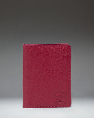Herschel Supply Co. Raynor Passport Holder in Cherry Red vegan leather, showing its textured finish and sleek, minimalist design.