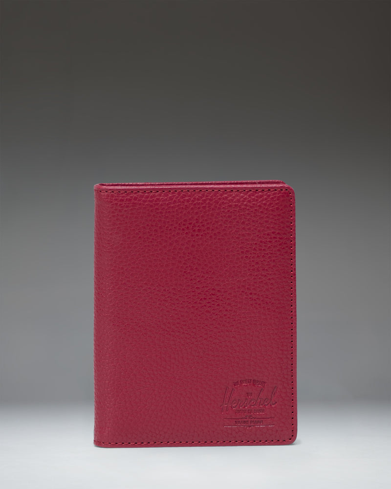 Herschel Supply Co. Raynor Passport Holder in Cherry Red vegan leather, showing its textured finish and sleek, minimalist design.