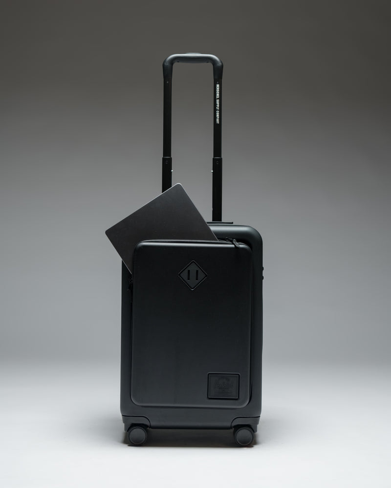 Herschel Heritage Hardshell Pro Large Carry On luggage in Black, shown from the front with a textured hard shell and retractable handle.