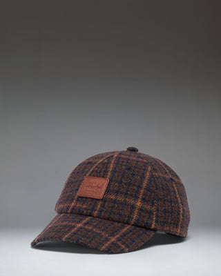 Herschel Supply Co. dark plaid backpack with tan brown straps and details, shown against a clean white background.