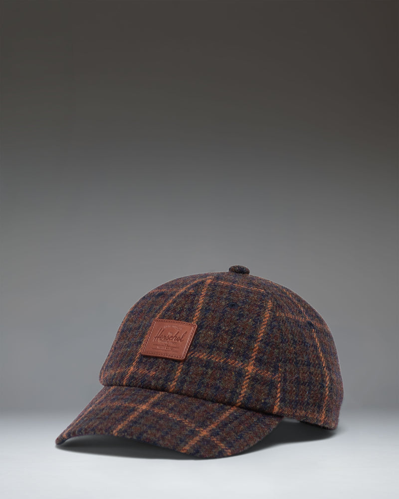 Herschel Supply Co. dark plaid backpack with tan brown straps and details, shown against a clean white background.