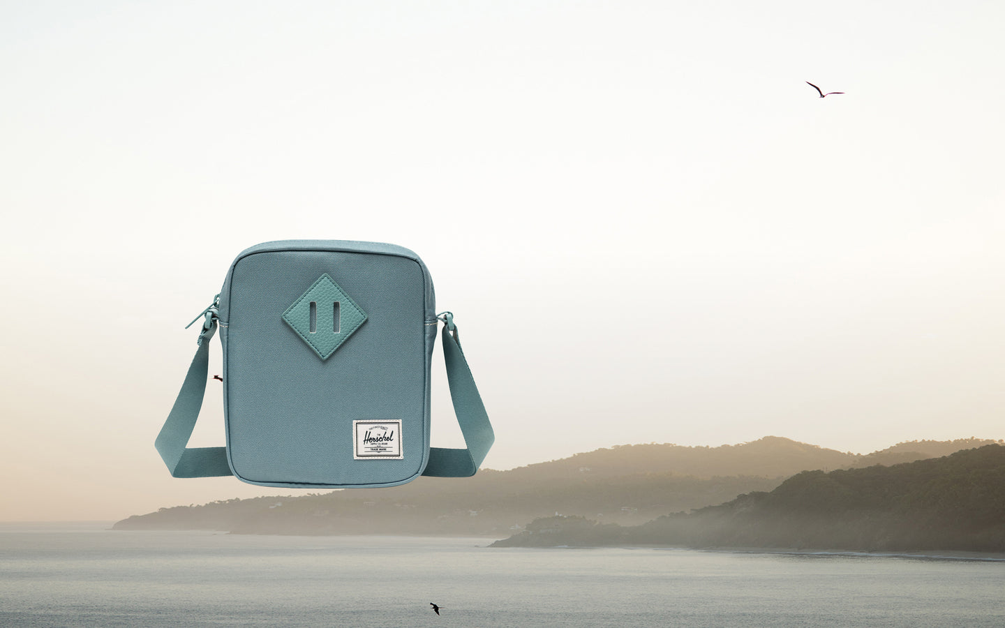 Front view of the black Herschel Heritage Crossbody bag with an adjustable strap and signature diamond detail.