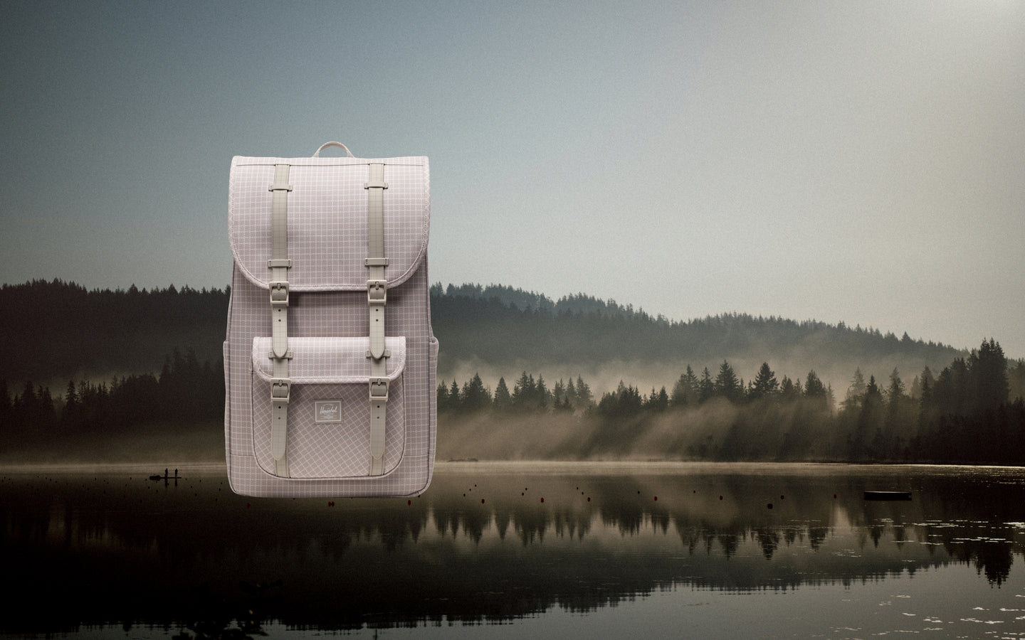 Herschel Little America Backpack in Grid London Fog gray pattern, featuring black rubber straps and a front storage pocket.