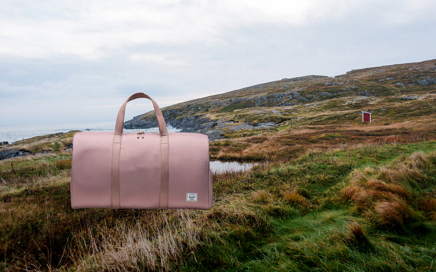 Herschel Novel Duffle bag in Ash Rose pink, shown from a front angle on a clean desktop background.