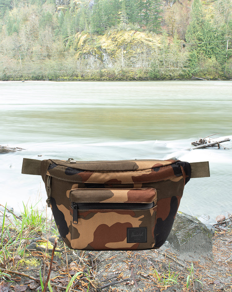 Herschel Supply Co. Pop Quiz Hip Pack in Woodland Camo with a Black Label, shown from the front.