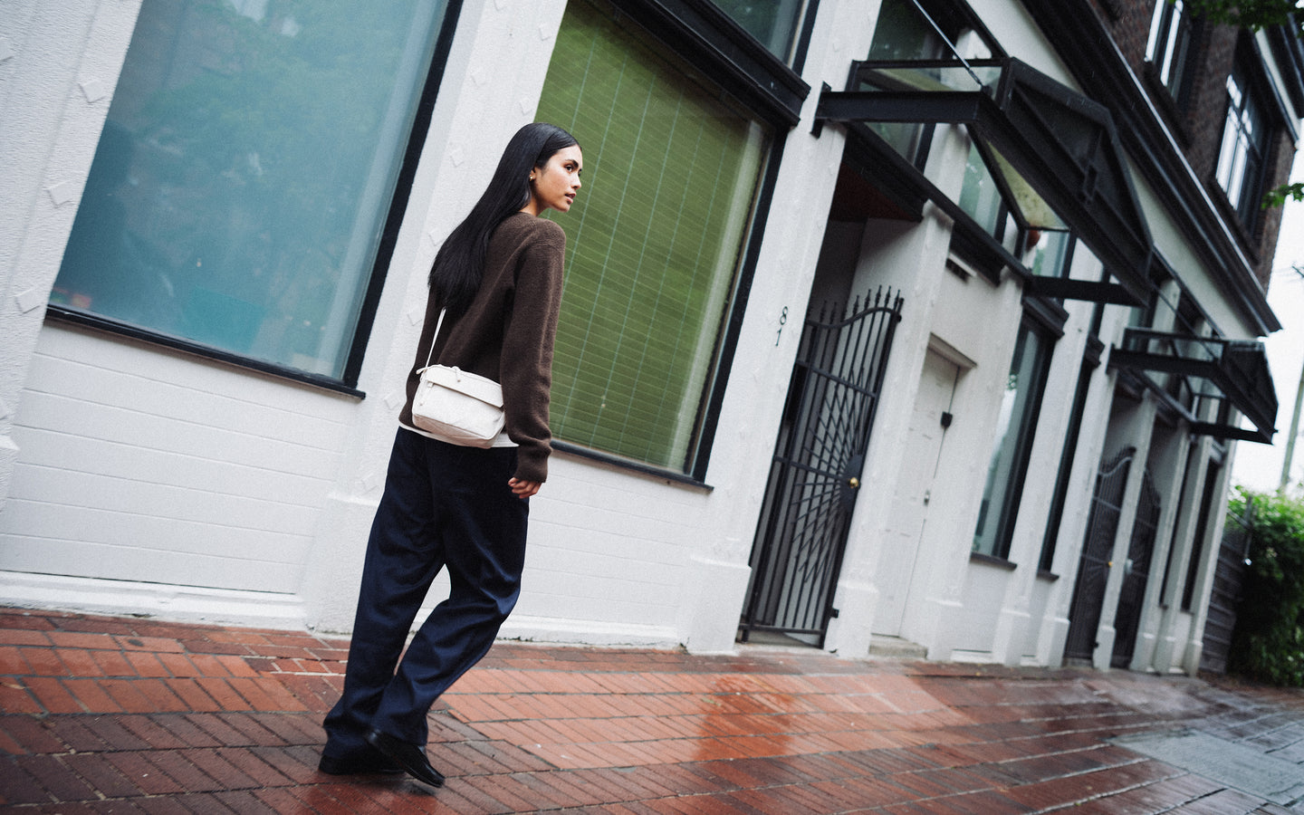 Herschel Supply Co. Alberni Crossbody bag in Moonbeam beige on a lifestyle desktop background.
