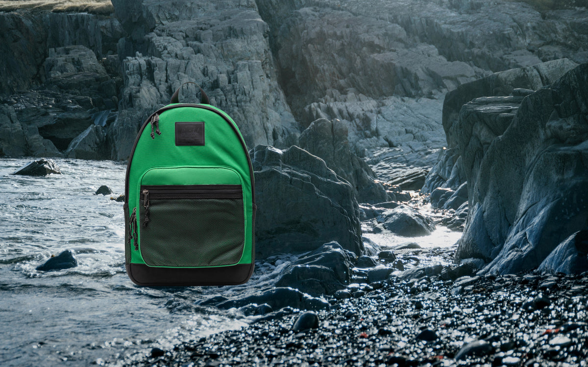 Herschel Supply Co Kaine Backpack in Varsity Pine green with black accents, front zipper pocket, mesh side pockets, and adjustable straps.