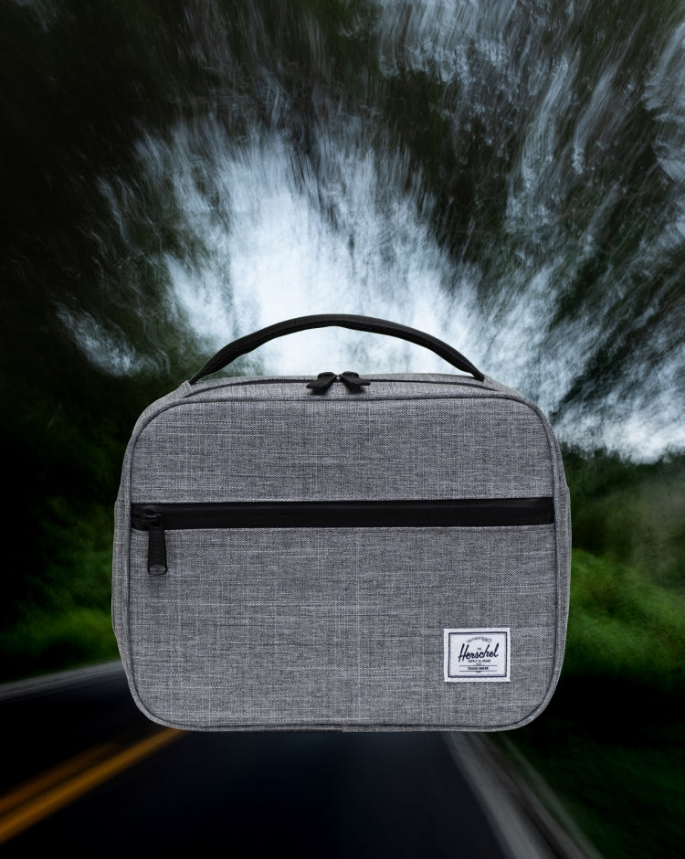 Herschel Supply Co. Pop Quiz Lunch Box in Raven Crosshatch grey, featuring a front pocket with a waterproof zipper and a reinforced top handle.