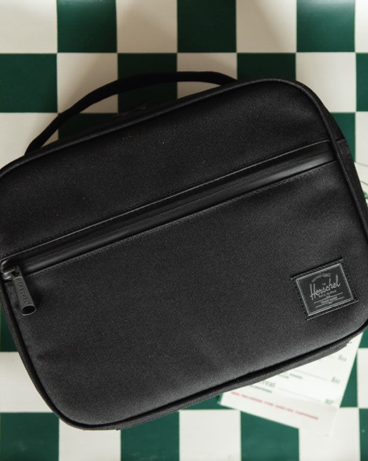 Herschel Supply Co. Pop Quiz Lunch Box in Black Tonal, shown from the front highlighting its clean, modern design and waterproof zipper details.