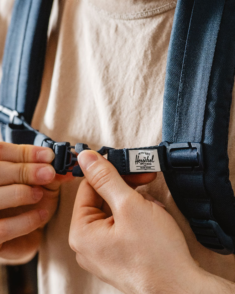 Herschel Supply Co. Sternum Strap in navy blue, designed to attach to backpack shoulder straps for added support.