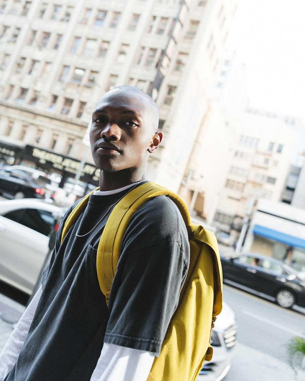 A man on a busy street wearing an Arrowwood Crosshatch Miller Backpack