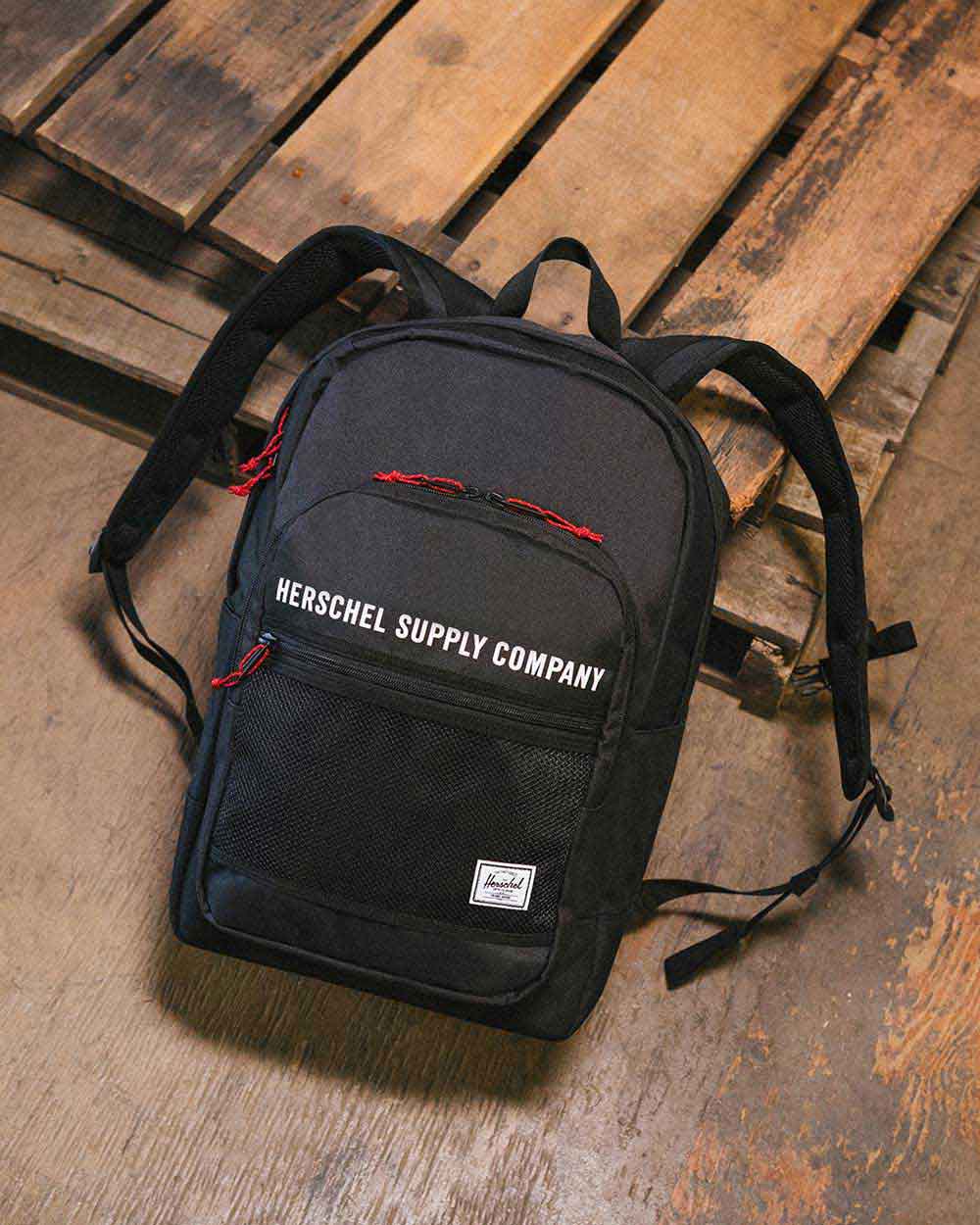 A black Kaine Backpack on a wood pallet