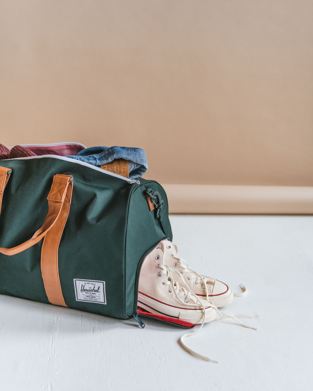 A Herschel Novel Duffle all packed up with some white sneakers hanging out the side-access shoe compartment