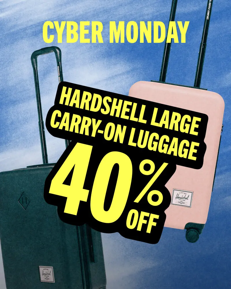 A black & ash rose Herschel Heritage Hardshell Large Carry On suitcases against a blue background with the title CYBER MONDAY informing that Hardshell Large Carry-On Luggage is 40% off.