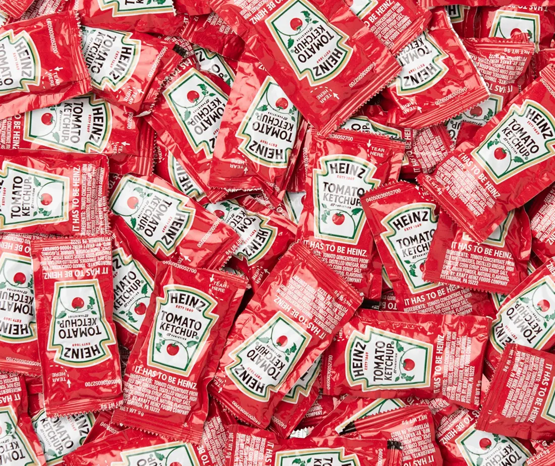 A line drawing of a backpack on a chair with a duffle bag on the ground next to it on the right and a plant to the left of the chair with a light blue background.