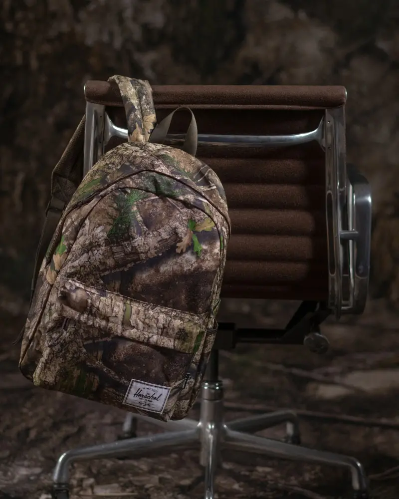 A Herschel Classic XL™ Backpack in APX™ Camo hanging off the back of an office chair