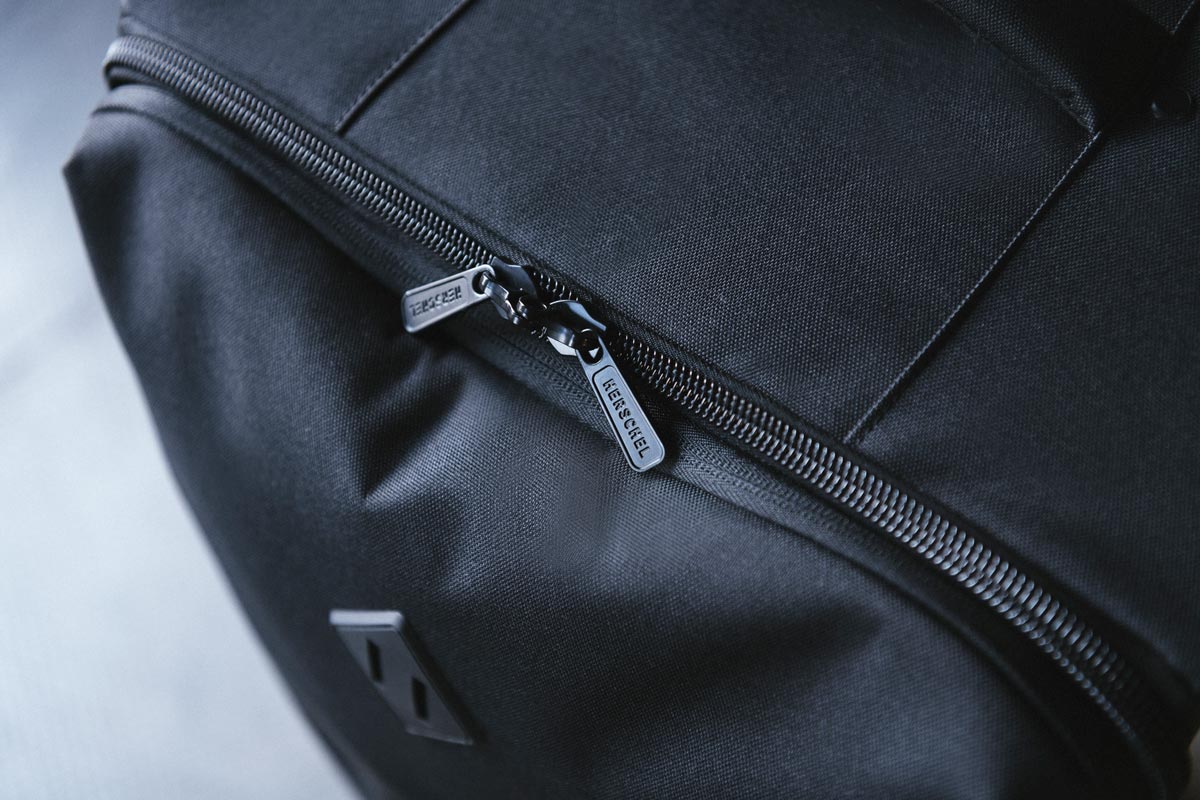 A shot of the zippered closure on the Highland Luggage Carry-On with its branded lockable zipper pulls